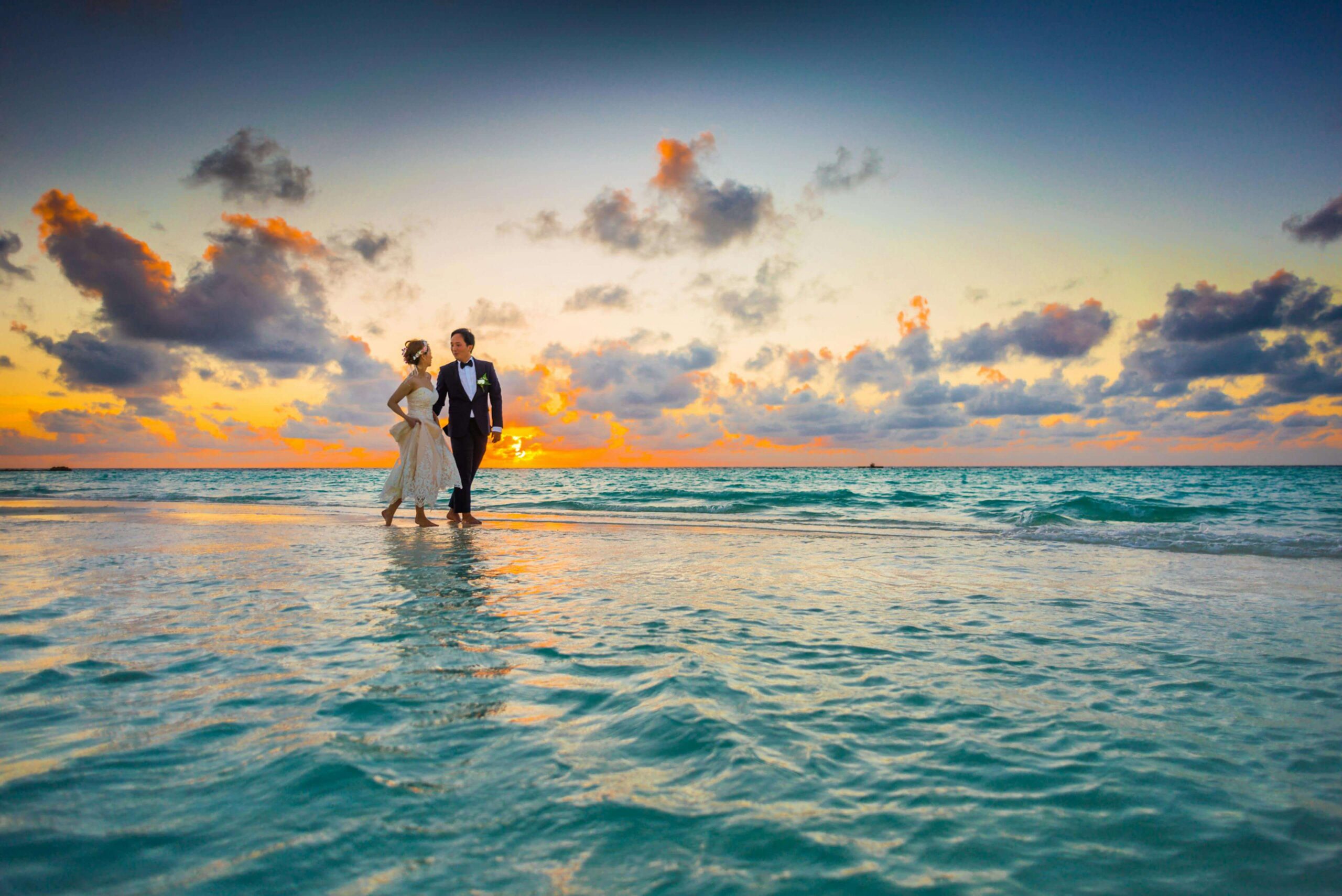 Couple in wedding attire walking on the beach